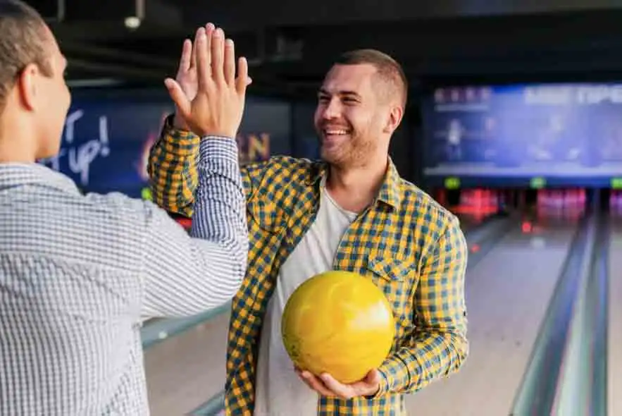Mænd der giver high five i bowlinghal