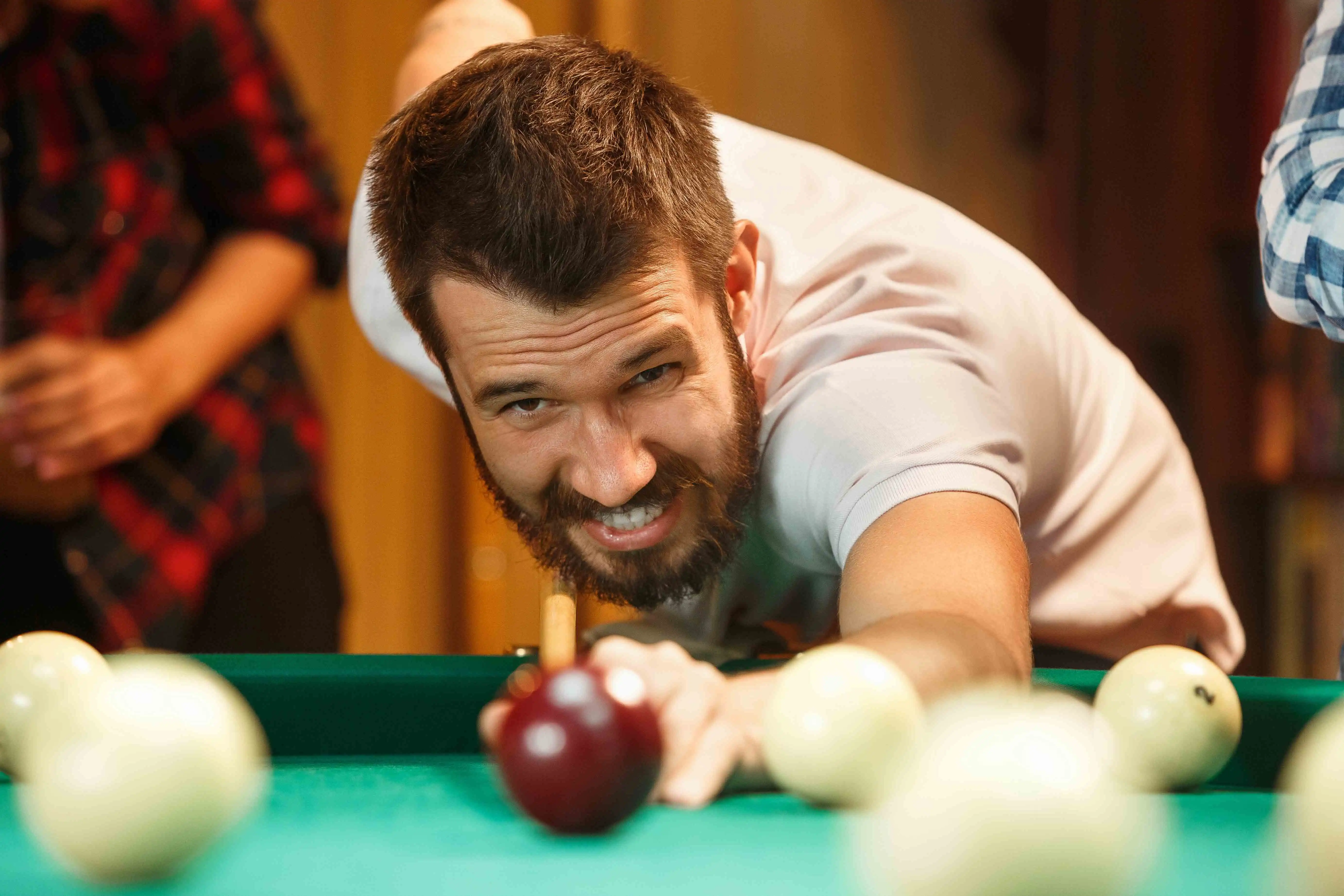 Mand der spiller billiard med mennesker omkring sig